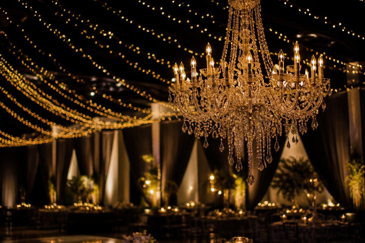 Crystal chandelier and warm string lighting over an event hall
